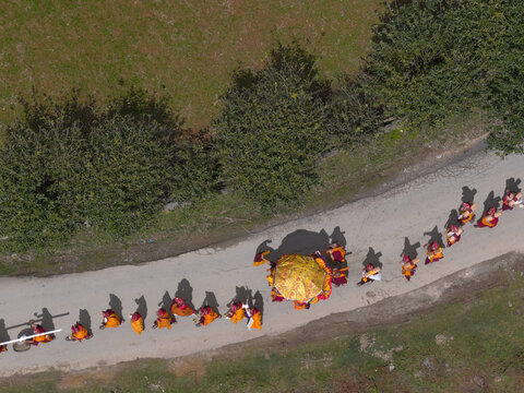 Gantey Monastery, Bhutan - 21 September 2025: Aerial view of a procession of monks in vibrant orange robes making their way along a winding path.