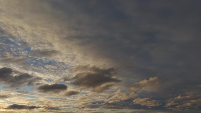 A drone aerial focused on a blue sky partially covered by soft, scattered clouds. The view emphasizes the atmosphere rather than the ground, showcasing gentle cloud formations, subtle light variations