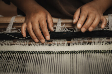 Chumey, Bhutan - 23 September 2025: View of nimble hands weaving intricate patterns on a traditional loom, the dark yarn contrasting against the light threads in Bumthang.