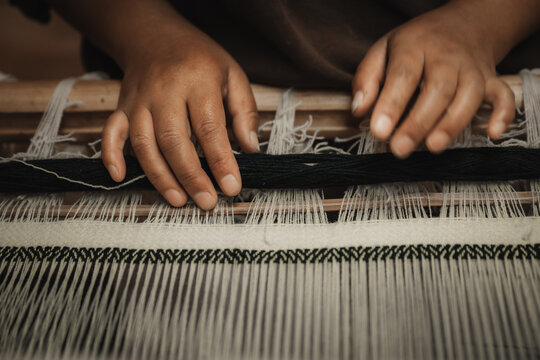 Chumey, Bhutan - 23 September 2025: View of nimble hands weaving intricate patterns on a traditional loom, the dark yarn contrasting against the light threads in Bumthang.