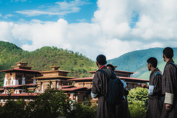 Punakha, Bhutan - 19 September 2025: View of the majestic Punakha Dzong, its white walls contrasting with the red roofs, set against a backdrop of verdant mountains and a bright sky.