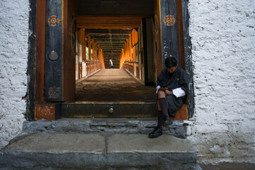 Punakha, Bhutan - 19 September 2025: View of a man sitting at the entrance of Punakha Dzong, the warm light illuminating the long corridor within.