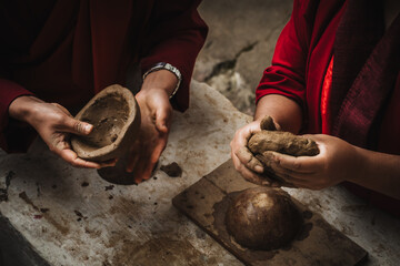 Walakha, Bhutan - 19 September 2025: View of hands shaping clay with patient precision, set against the backdrop of Sangchhen Dorji Lhuendrup Lhakhang Nunnery.