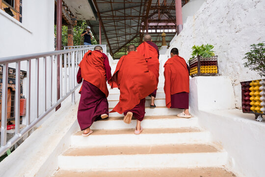 Walakha, Bhutan - 19 September 2025: View of monks in vibrant red robes ascending the pristine white steps of Sangchhen Dorji Lhuendrup Lhakhang Nunnery.