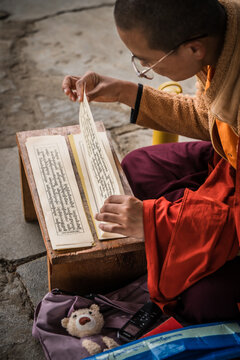 Walakha, Bhutan - 19 September 2025: View of a nun engrossed in scriptures at Sangchhen Dorji Lhuendrup Lhakhang Nunnery, the pages illuminated in the soft light.
