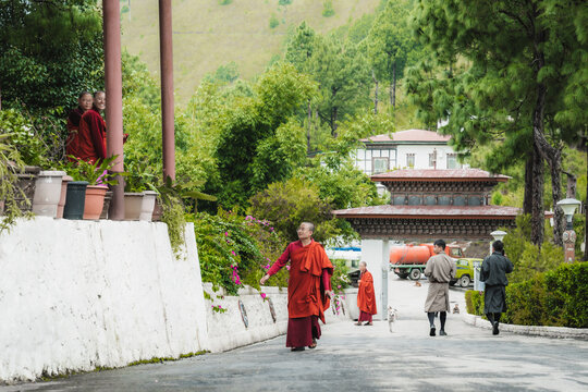 Walakha, Bhutan - 19 September 2025: View of Sangchhen Dorji Lhuendrup Lhakhang Nunnery as monks in vibrant robes walk along the paved path.