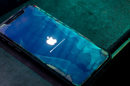 Concept of an old iPhone 11 still receiving the latest iOS software update, shown with a cracked screen. Editorial use only.