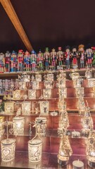 This photo captures a festive Christmas market stall displaying two charming holiday traditions: a vibrant row of colorful nutcracker figurines lined up on the top shelf
