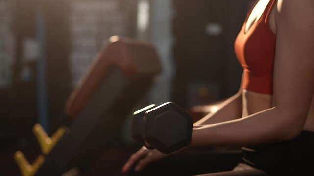 Health conscious Asian woman lifting weights at the gym to strengthen arm muscles and improve fitness. Ideal for concepts of strength training, healthy lifestyle, women wellness, and self care.