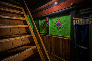 Ha, Bhutan - 26 September 2025: View of wooden stairs ascending beside vibrant green walls adorned with colorful floral designs in a traditional Bhutanese home.