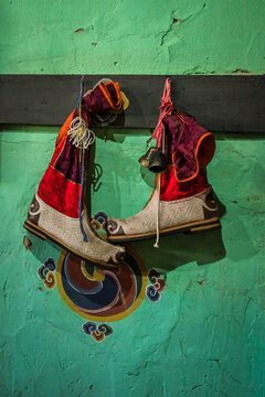 Ha, Bhutan - 26 September 2025: View of vibrant ceremonial boots hanging against a textured, turquoise wall, accented by traditional Bhutanese motifs and dark wooden beams.