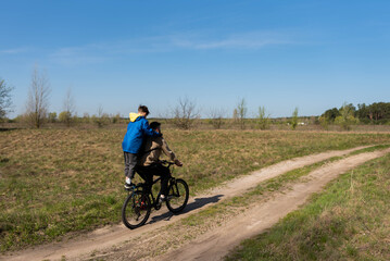 Father rides his son on the bike rack in the meadow