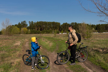 Father and young son riding bicycles together in a meadow