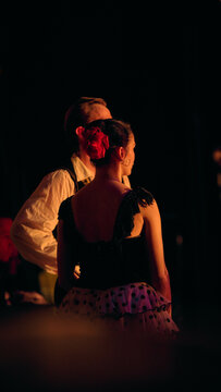 Ballet performers waiting in wings under warm stage illumination. Concept of partner positioning, cue tracking and synchronized readiness before active choreography.