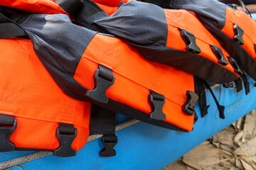 Bright orange life jackets stacked on blue boat, ready for water adventure. Safety equipment with black straps and buckles provides sense of preparedness for aquatic sports
