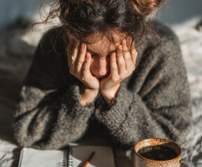 Overhead Frustration: Woman with Head in Hands, Notebook and Coffee Mug on Bed