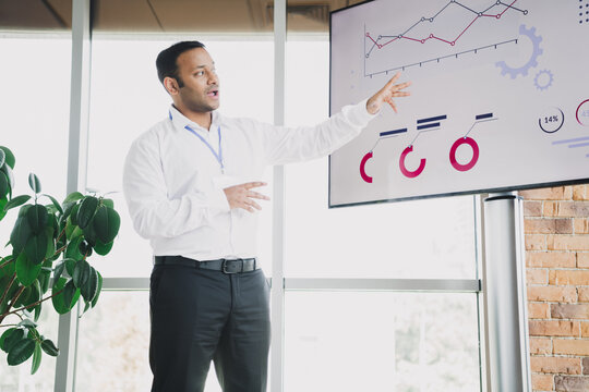 Young handsome business professional giving a presentation in a modern loft office with charts - Powered by Adobe