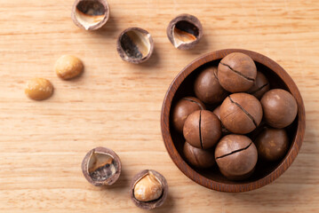 Macadamia nuts in a bowl on wooden background, Table top view