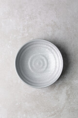 Top view of grey ceramic plates on a marble table, handmade grey ceramic plate on a white background