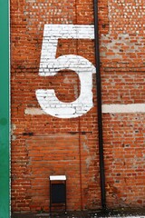 The number 5 on the brick wall of the house in the city center.
