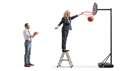 Man clapping and woman climbing a ladder and scoring with a basketball