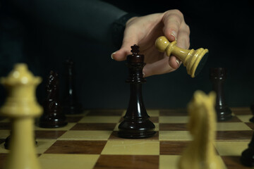 Chess player moves pawn to capture king during a game in a dimly lit room in the evening