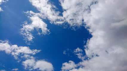 Wispy and fluffy clouds drift across a vivid blue sky, creating a peaceful and visually striking scene.