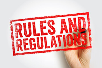RULES AND REGULATIONS printed in a bold red stamp, applied by a hand, symbolizing structure, policy, compliance, governance, and required standards within an organized system