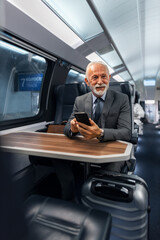 Fototapeta premium Senior Businessman Traveling on a Train Using a Smartphone