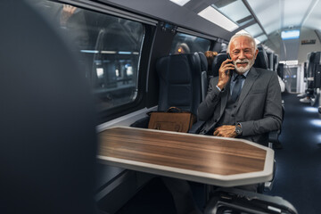 Professional Senior Man Talking on Phone During Train Journey