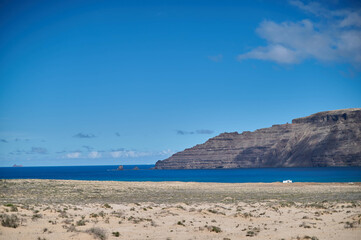 Obraz premium La Graciosa Island, Canary Islands. Tranquil volcanic landscape with pristine beaches and traditional white village under a clear blue sky.