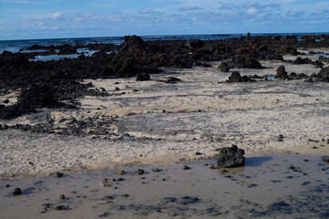 Caletón Blanco in Lanzarote, Canary Islands. White sand and clear turquoise water of the natural tide pools along the rugged volcanic coastline.