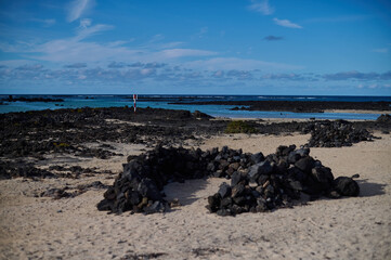 Caletón Blanco in Lanzarote, Canary Islands. White sand and clear turquoise water of the natural tide pools along the rugged volcanic coastline.