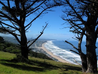 Scenic hilltop view over the Wilderness coastline in South Africa with ocean waves, beach, trees and coastal landscape.