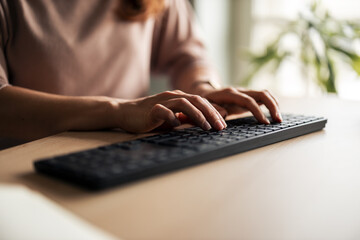 Person Typing on a Computer Keyboard in a Sunlit Office