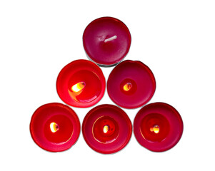 Six red candles. Five candles are lit with different brightness. Different amounts of melted wax in...