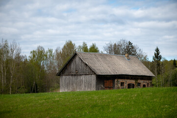 Old wooden barn standing on bright green Latvian meadow