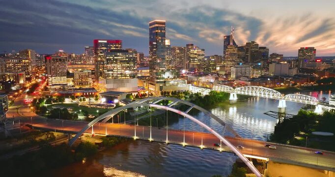 Downtown district of Nashville city in Tennessee, USA at night. Cars drive on Korean Veterans Memorial Bridge over Cumberland river. American travel destination.