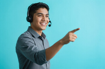 A smiling young man wearing a headset and pointing to the right against a blue background.