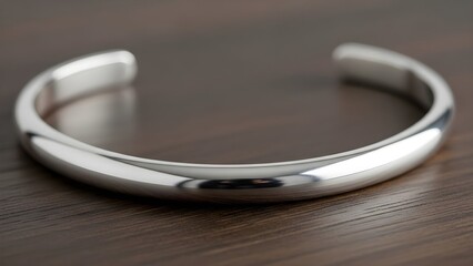 Shiny silver bangle bracelet on dark wood surface elegant jewelry