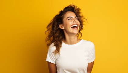 Joyful young woman laughs wholeheartedly against a vibrant yellow background showcasing happiness and vibrant energy