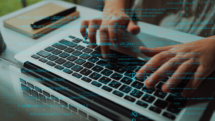 A close-up view of hands typing on a laptop keyboard, immersed in a modern tech workspace filled with digital data and programming elements, symbolizing innovation. Xenic