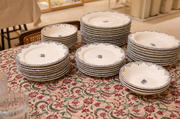 Stacked ceramic plates on floral tablecloth in dining room setting