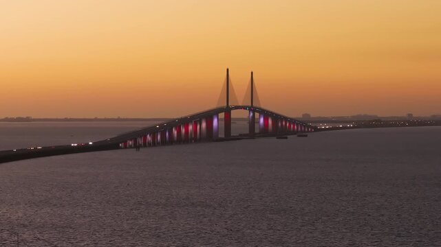 Highway road with driving traffic cars at sunset on Sunshine Skyway Bridge over Tampa Bay in Florida. Transportation infrastructure in USA
