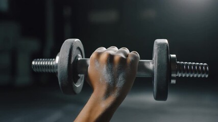 Dumbbell Grip. Fitness Resolutions - New Beginnings & Fresh Start. A young man's hand with chalk dust gripping a brand new 5kg dumbbell set against a dark blurred gym floor backdrop.
