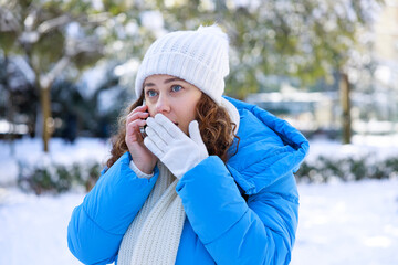 Woman in blue winter jacket speaking on phone in a snowy park