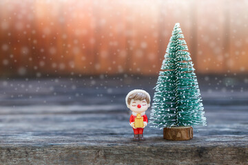 Santa boy holding gift box with Christmas tree over blurred wood background, Christmas card background idea