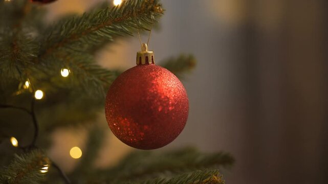 a hand putting christmas ball into christmas tree