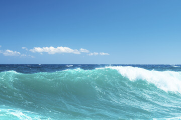 Fototapeta premium Beautiful ocean wave crashing under clear blue sky, creating serene and refreshing atmosphere