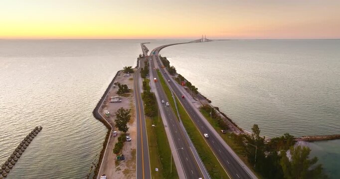 Oceanfront campsite with RVs and motorhomes parked near iconic Florida Sunshine Skyway Bridge bridge at evening time.
